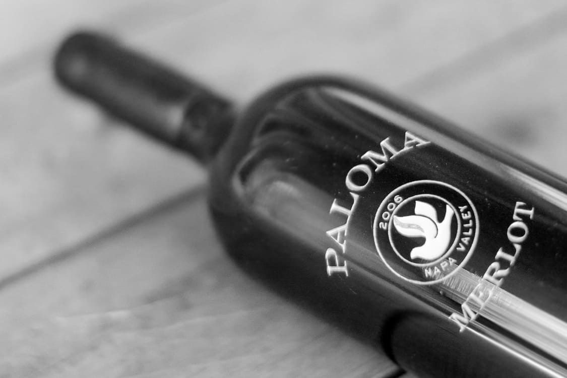 A bottle of paloma merlot sits on a wooden table