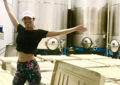 A woman is standing in front of a bunch of tanks with her arms outstretched.