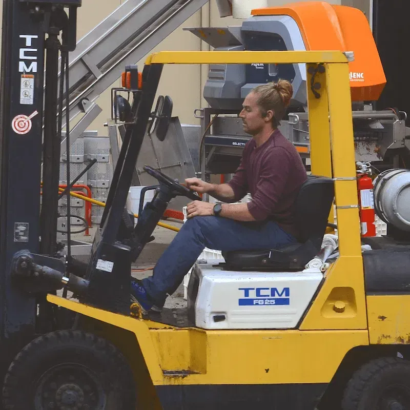 A man is driving a yellow tcm forklift