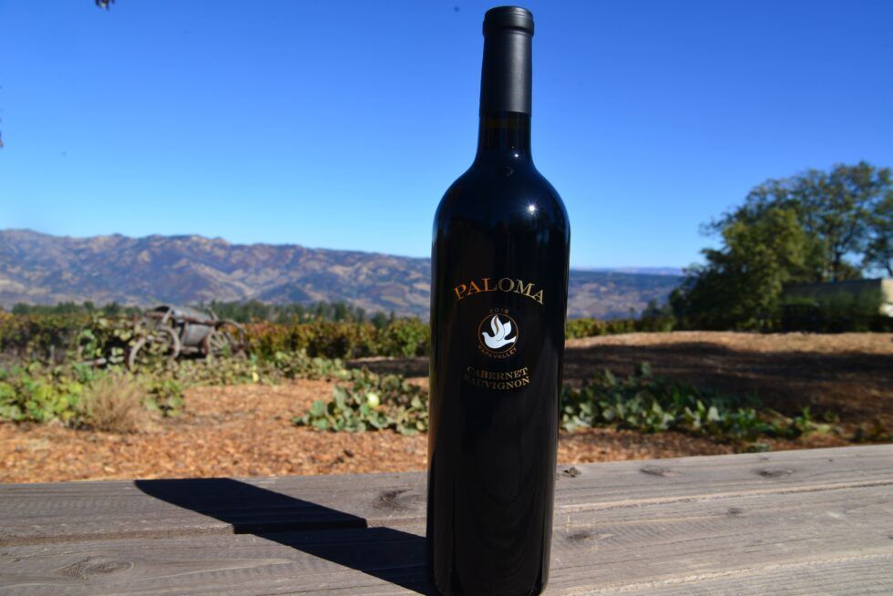 A bottle of paloma wine is sitting on a wooden table.