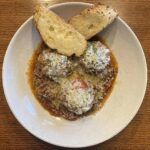 A white plate topped with meatballs and bread on a wooden table.