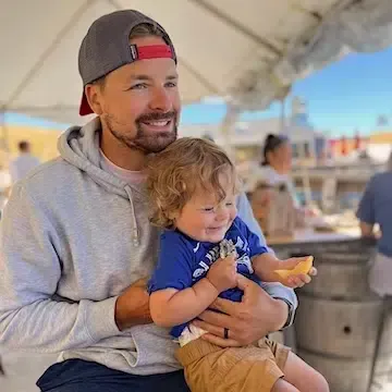 A man is holding a baby in his arms and the baby is smiling.