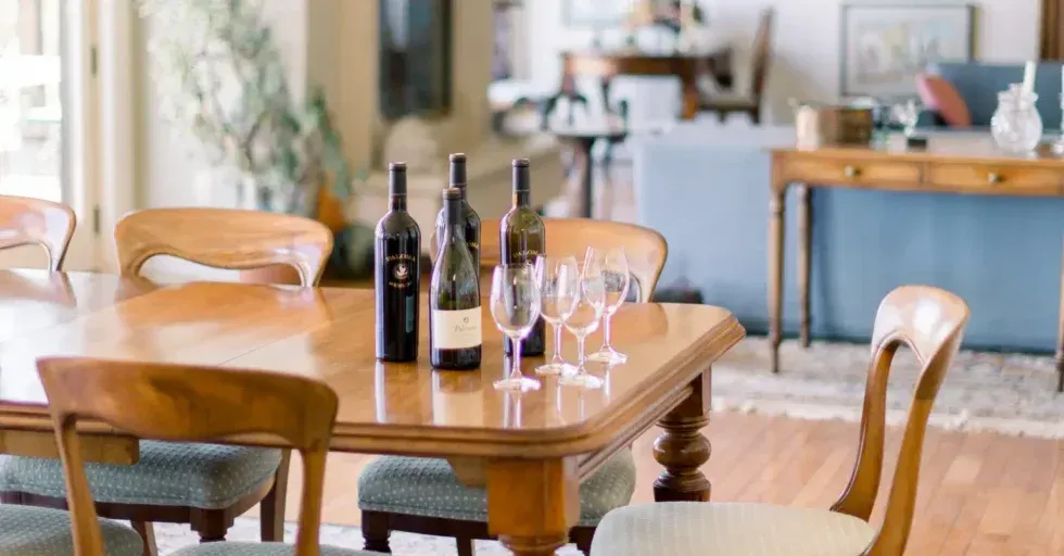 A dining room table with bottles of wine and glasses on it.