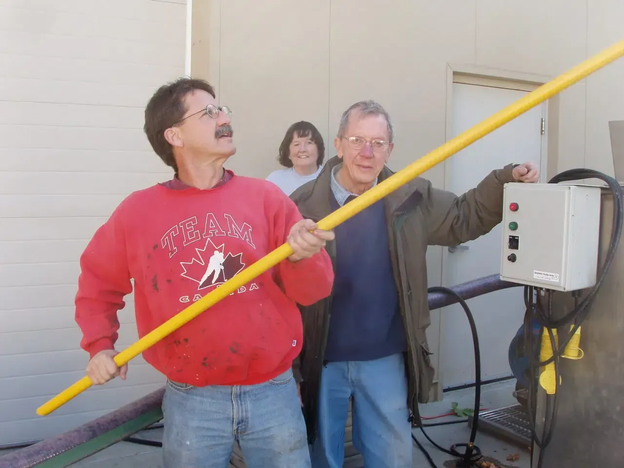 A man in a red sweatshirt is holding a yellow pole