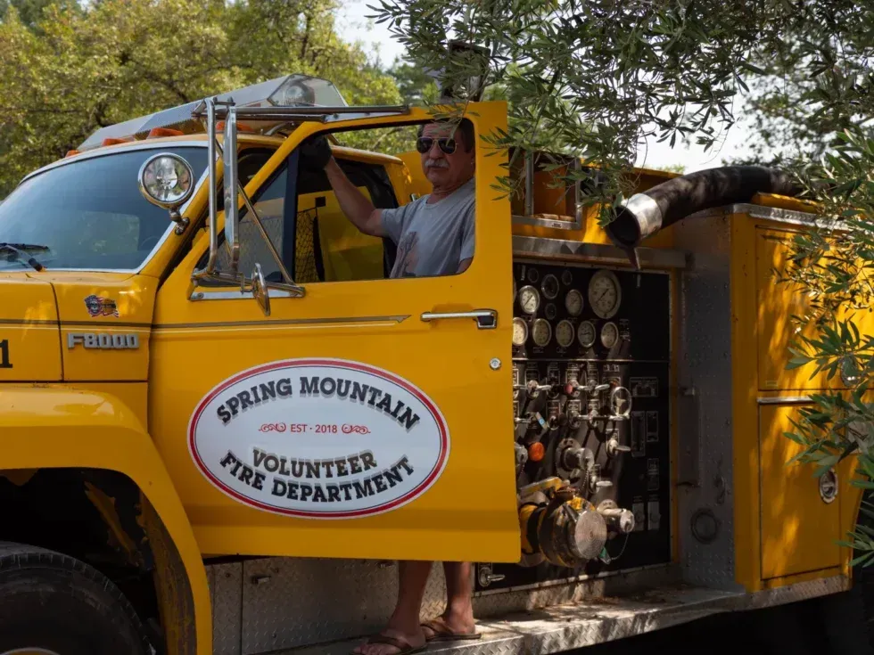 A man is driving a yellow spring mountain volunteer fire department truck