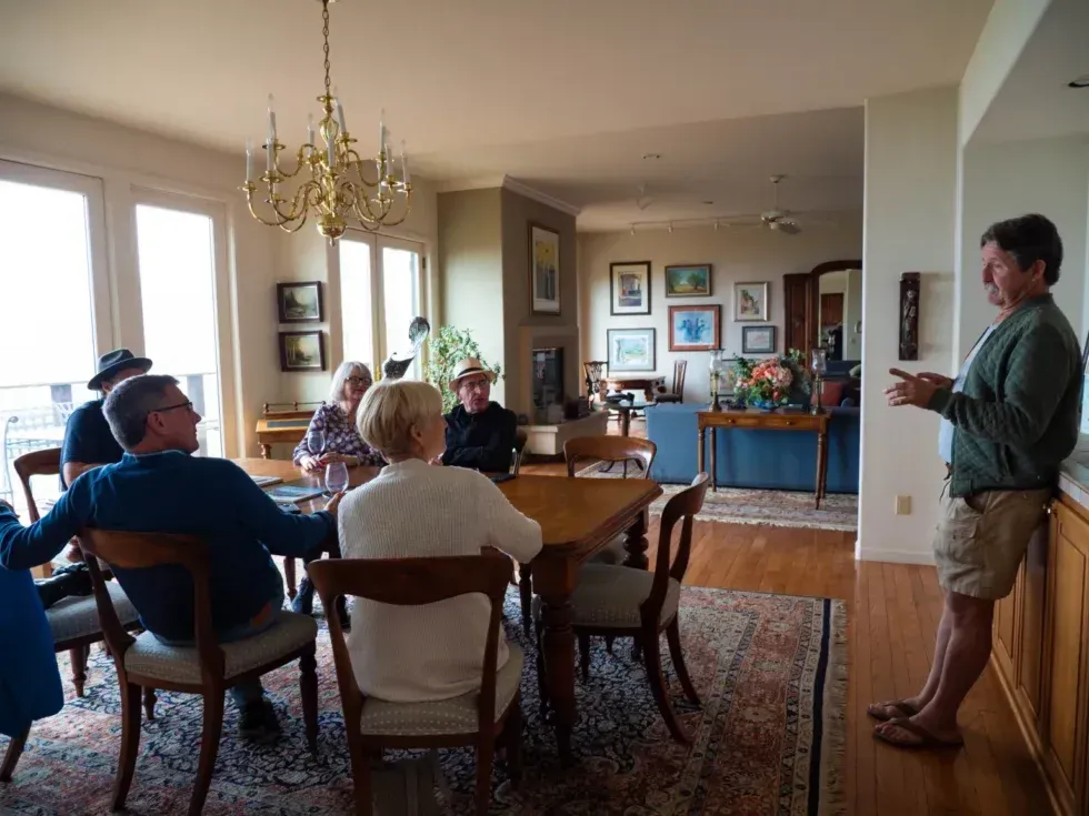 A group of people are sitting around a table in a living room.
