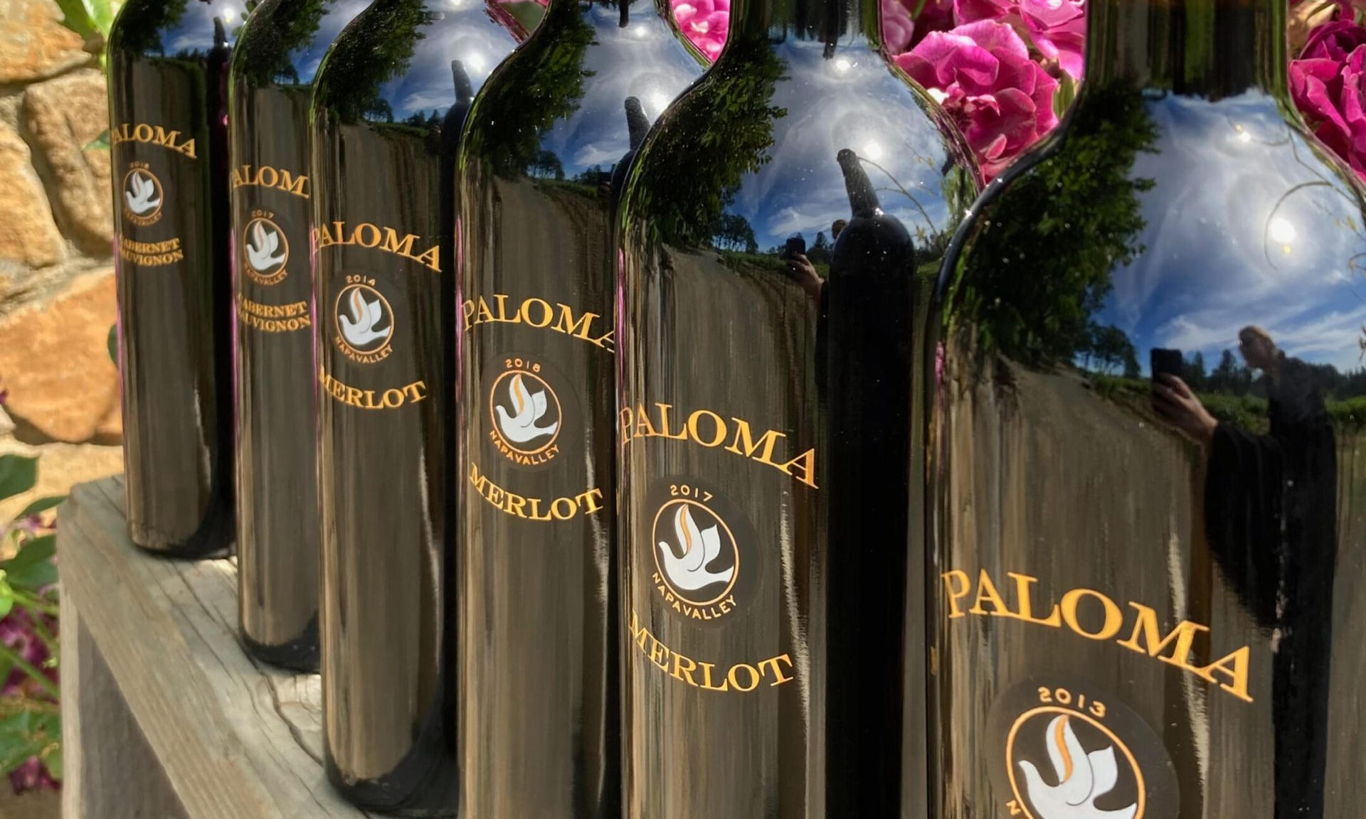 A group of people are standing in a wine cellar surrounded by wine barrels.