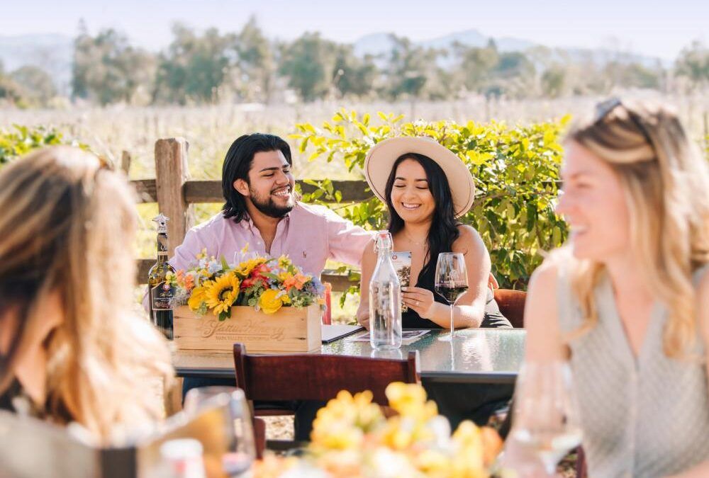 A group of people are sitting at a table drinking wine.