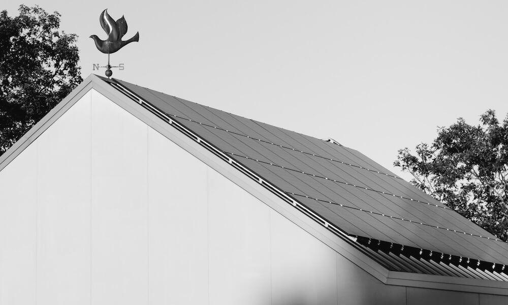A black and white photo of a roof with solar panels