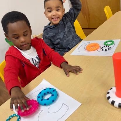 Two young boys are sitting at a table playing with toys