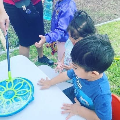 A boy in a blue shirt is sitting at a table playing with bubbles.