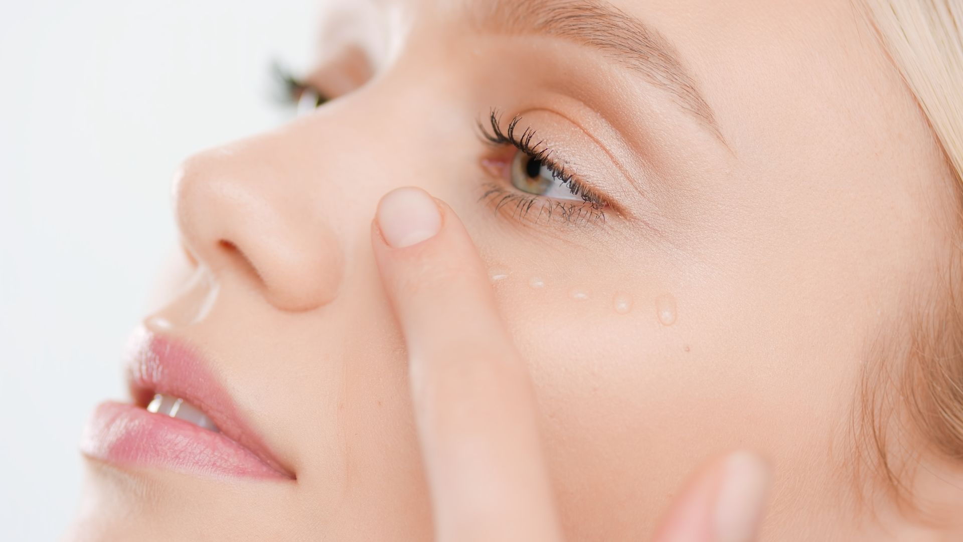 A close up of a woman applying foundation to her face.