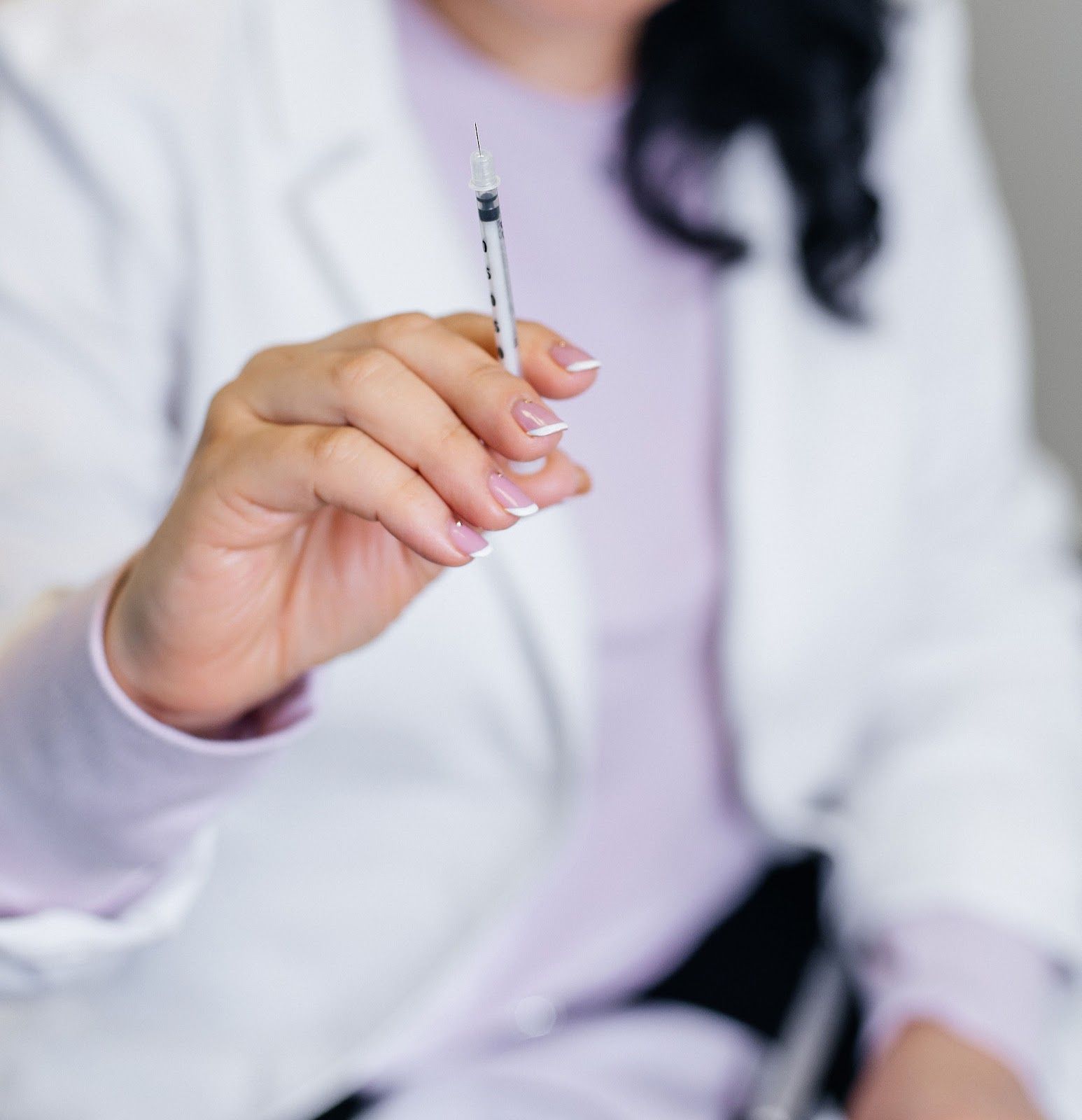 Person holding a syringe, likely preparing for an injection.