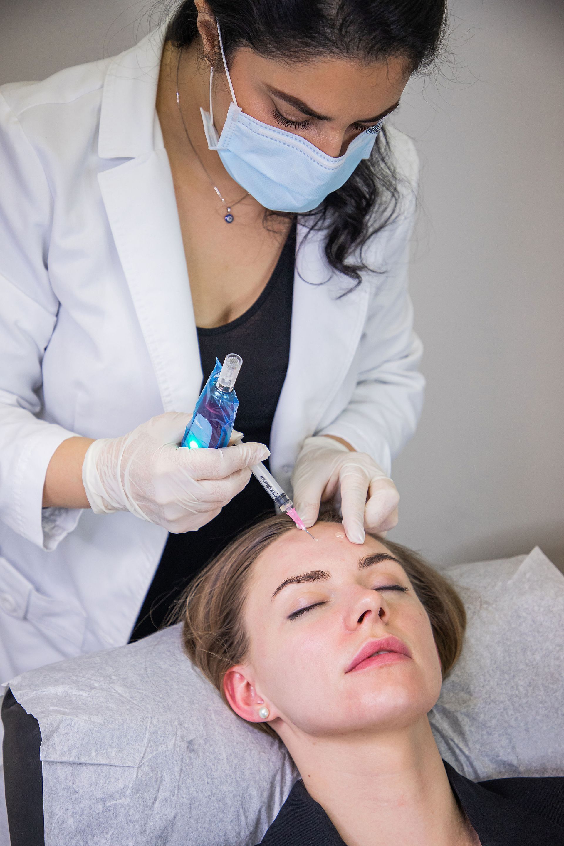 A woman is getting a botox injection in her forehead.