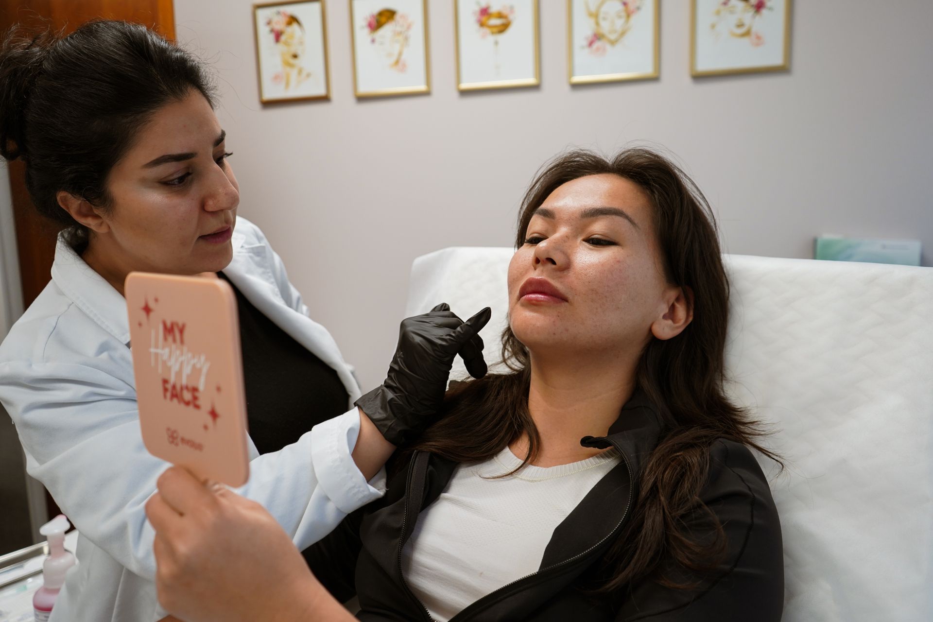 A woman is laying on a bed looking at her face in a mirror.