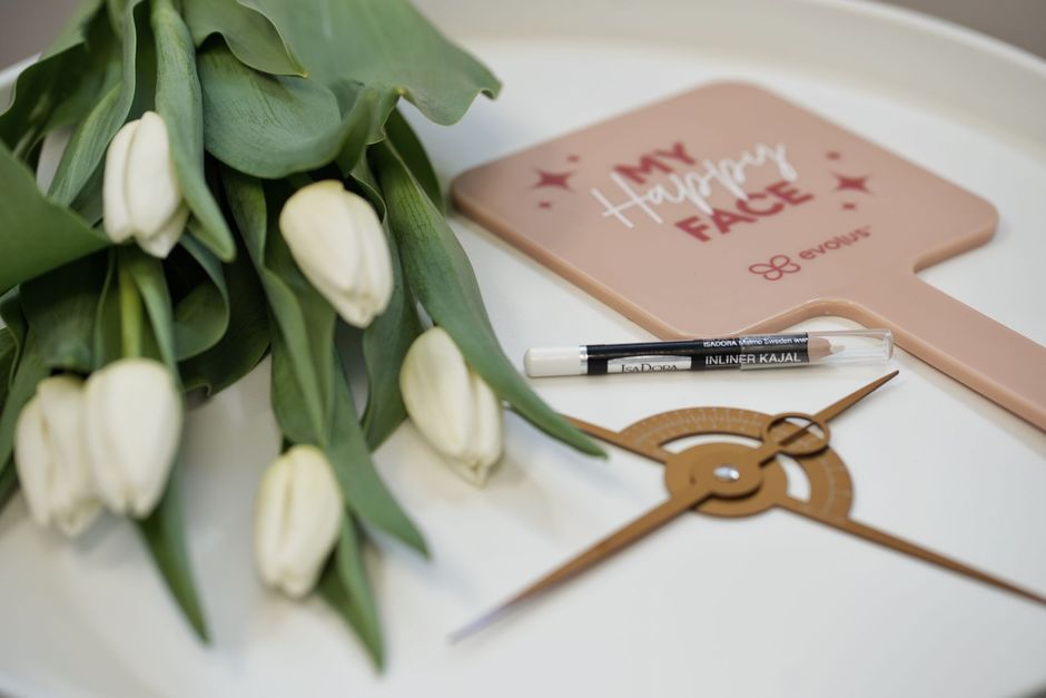 A clock is sitting on a table next to a mirror and flowers.