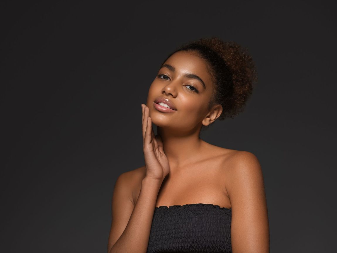 a beautiful woman touching her face with a black background