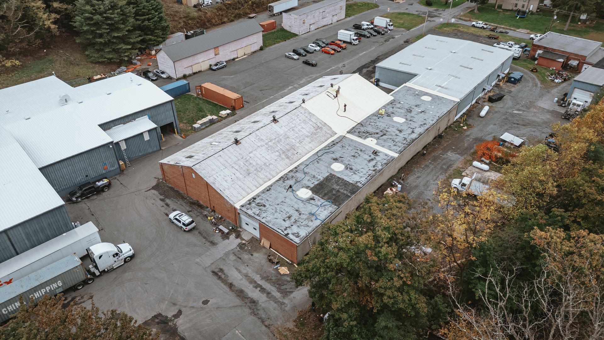 Aerial view of commercial buildings, warehouses, and parked trucks in a business park.