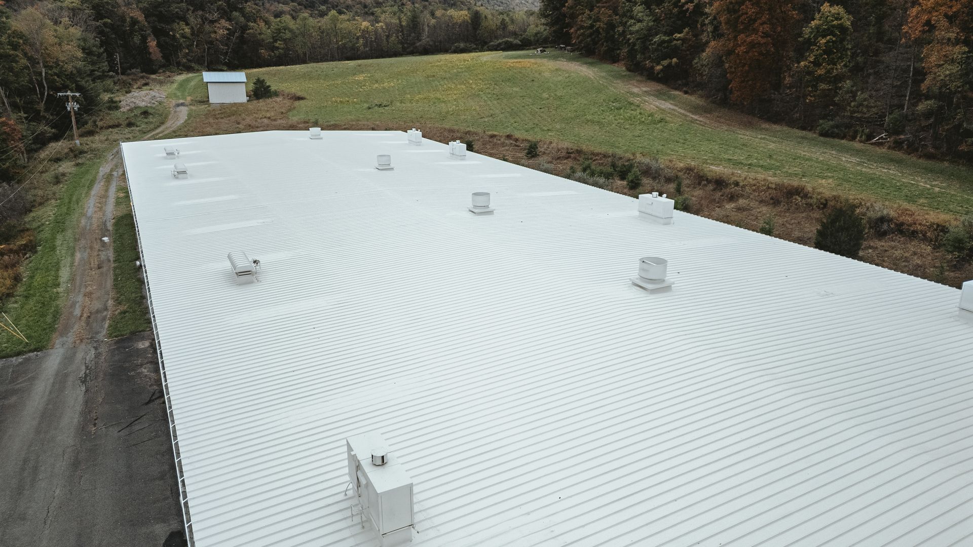 Overhead view of a large, white building roof covered with evenly spaced vent structures