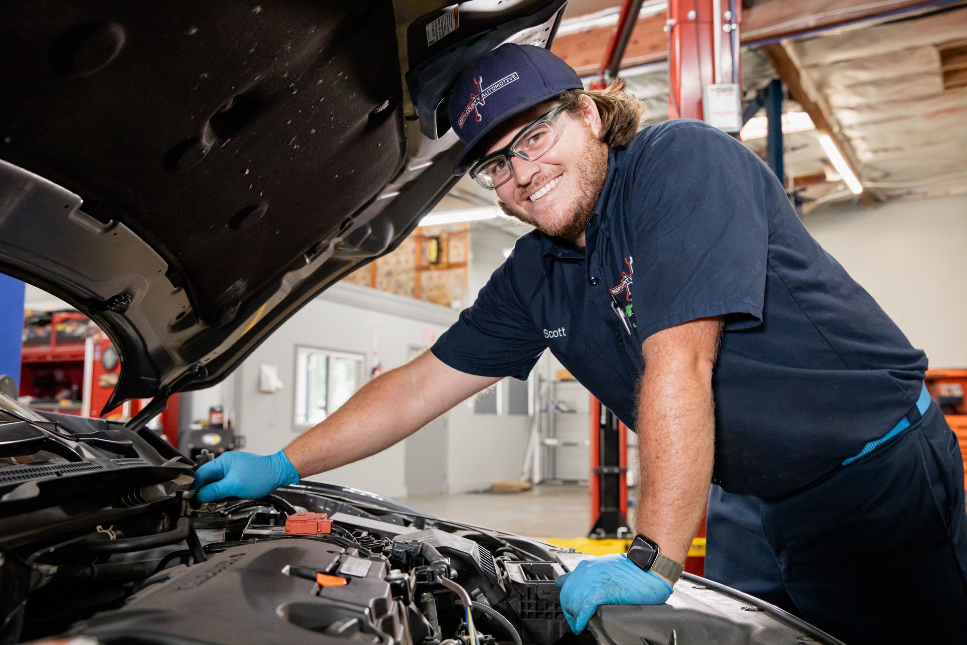 A man is working on the engine of a car in a garage.