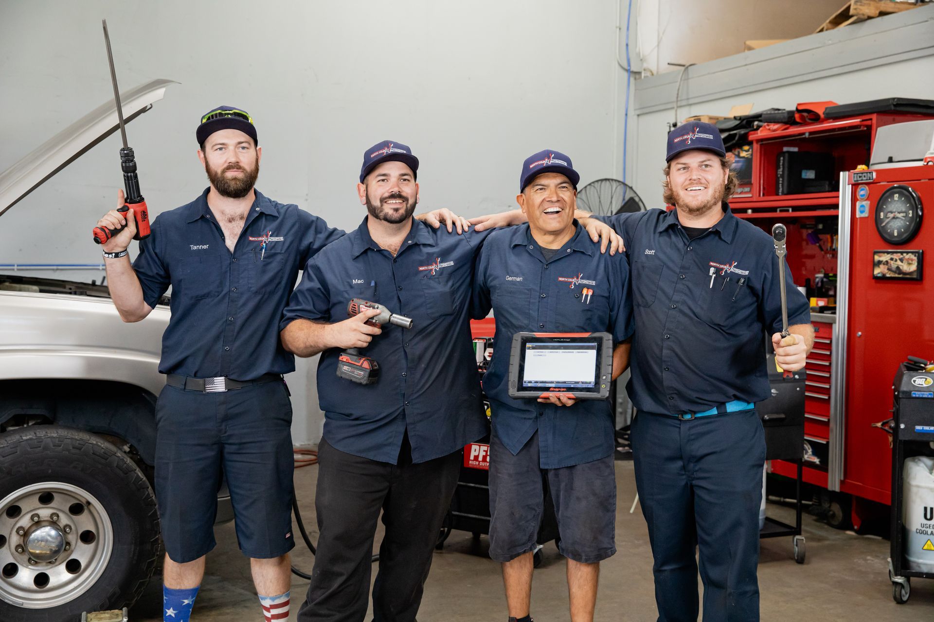 A group of mechanics are posing for a picture in a garage.