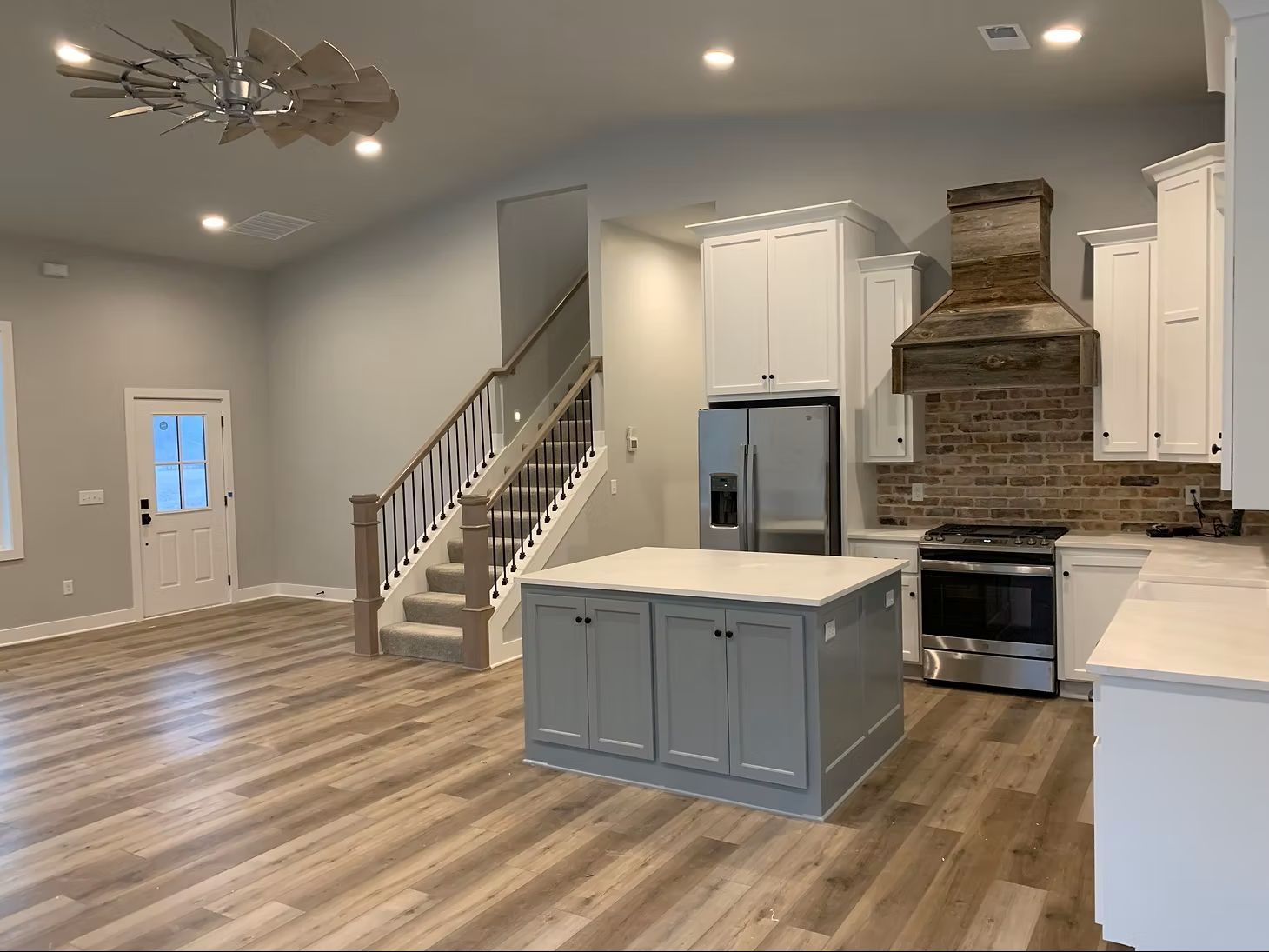 A gray house with a screened-in porch on a grassy field under a cloudy sky.