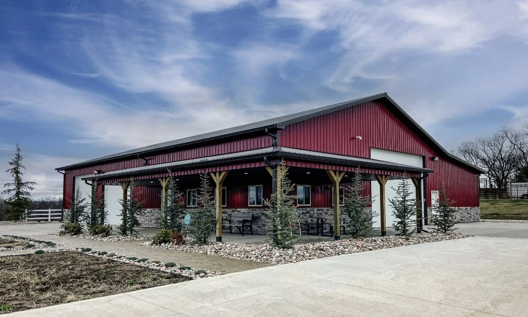 Tan and brown metal barn with a covered entrance under a clear blue sky.