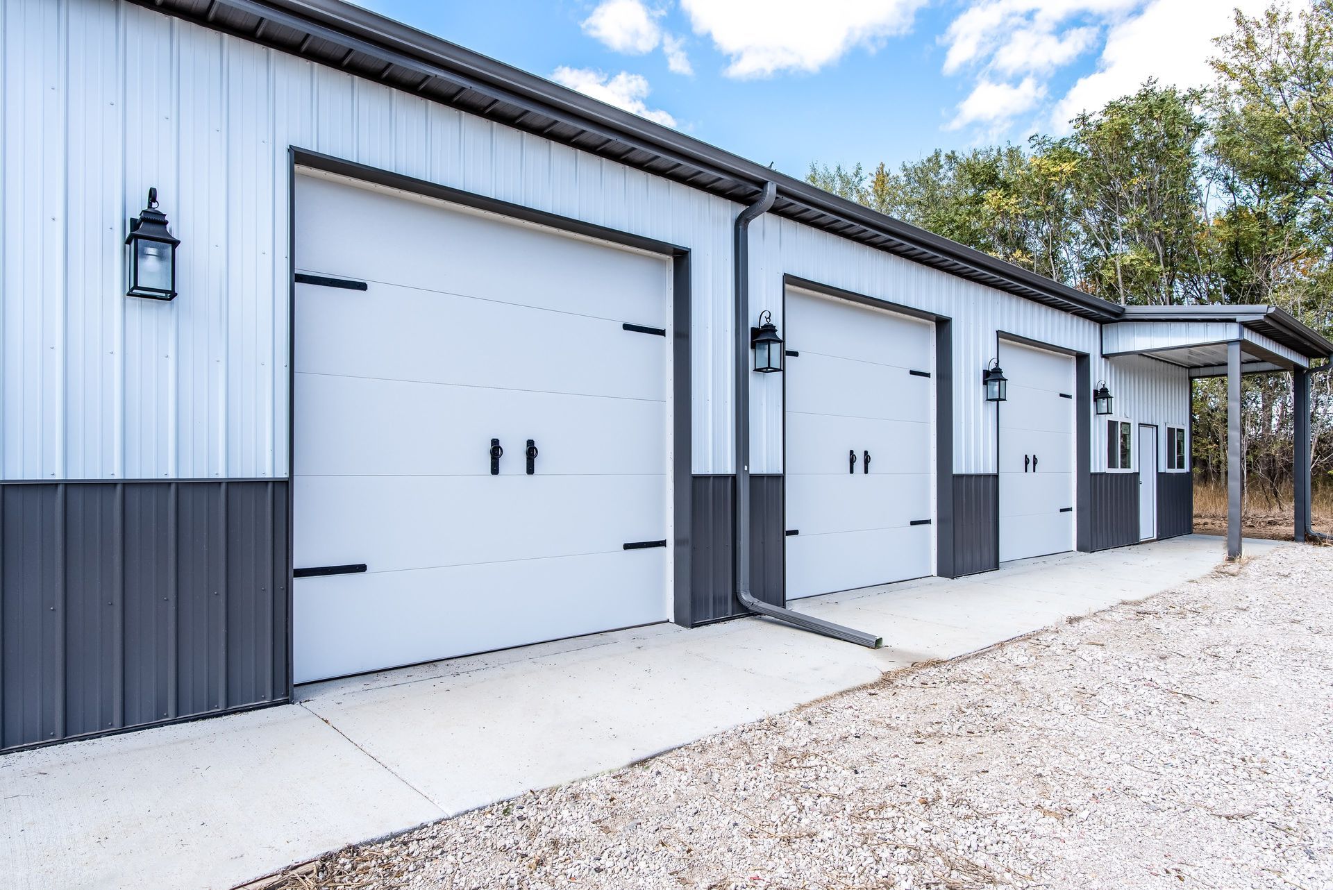 White and gray garage building with three doors, black accents, and a covered side entrance.