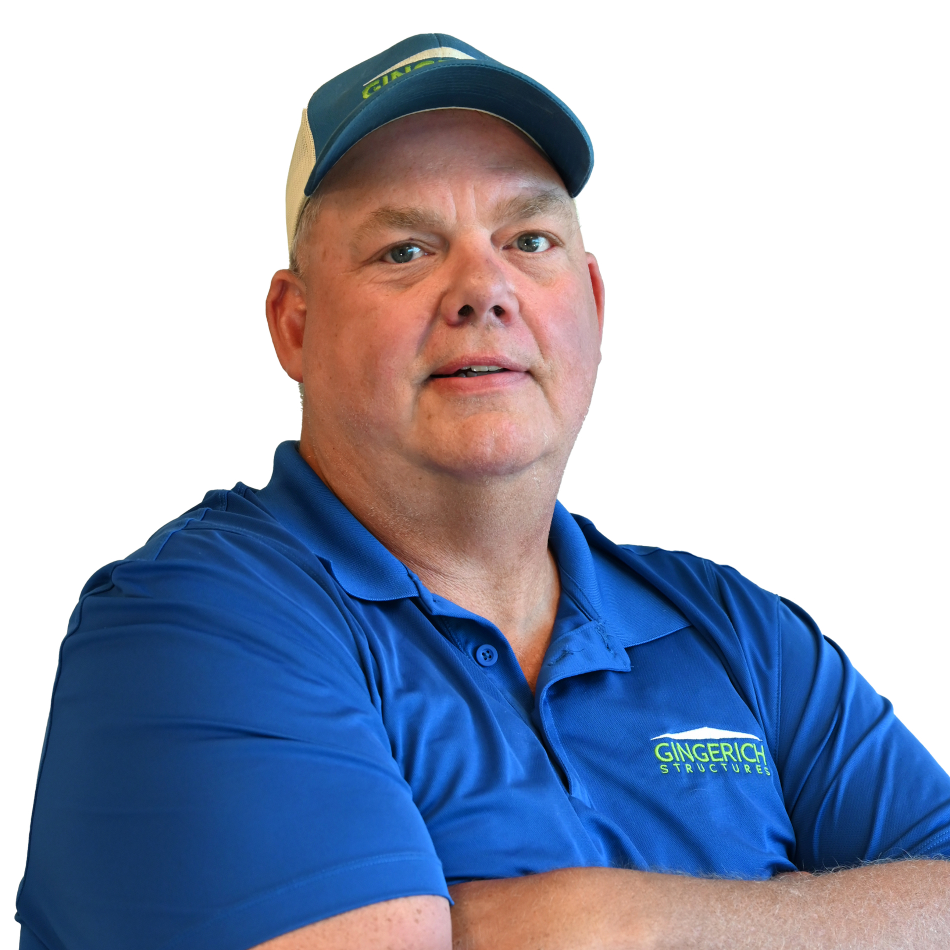 Man in blue shirt and cap, arms crossed, smiling.