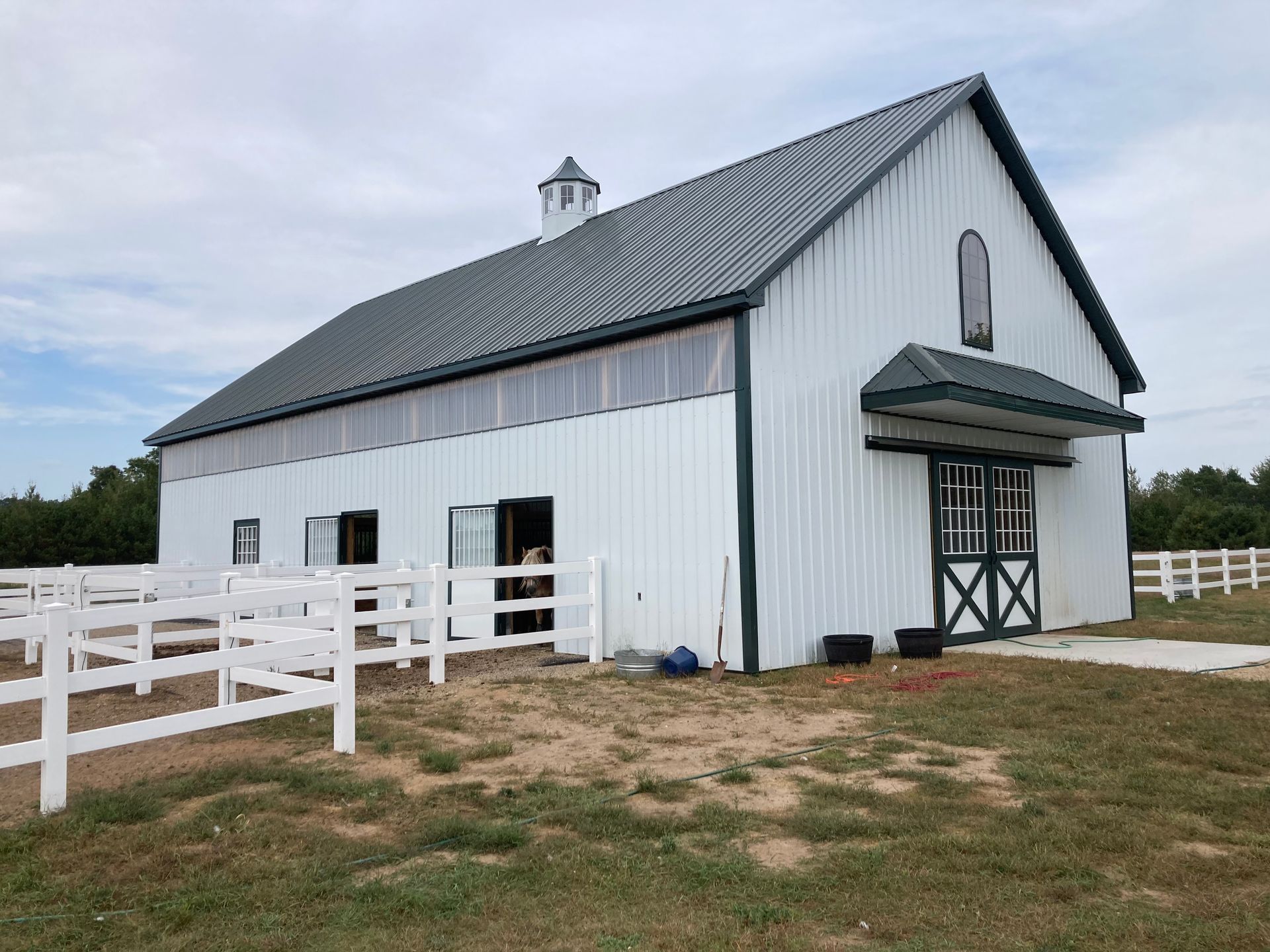 Tan and brown metal building with a brown roof and a porch, under a clear blue sky.