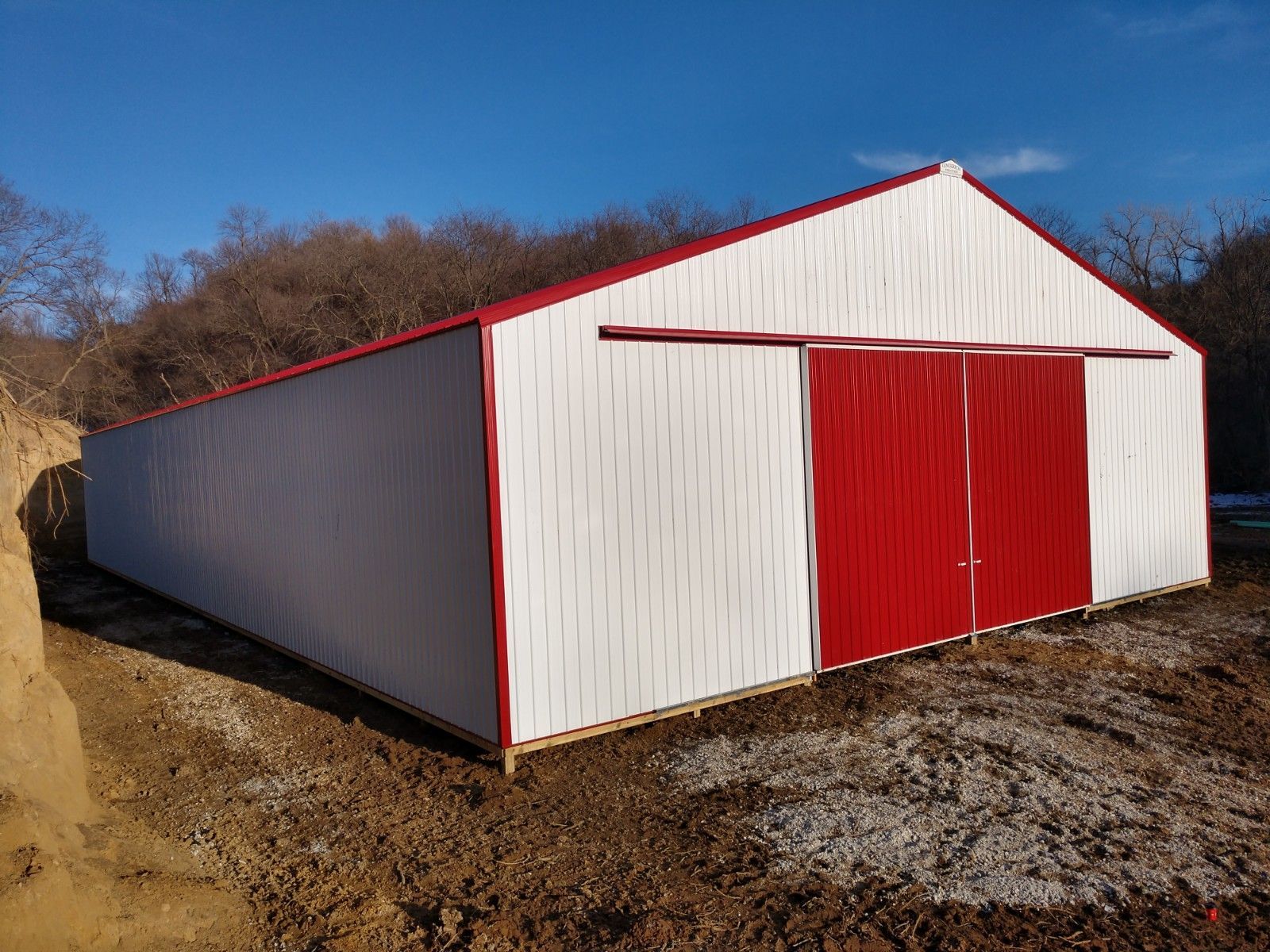 Tan and brown metal building with a brown roof and a porch, under a clear blue sky.