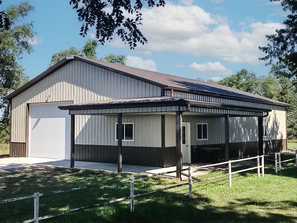 Metal building with covered porch and garage door, brown and beige colors, sunny day.