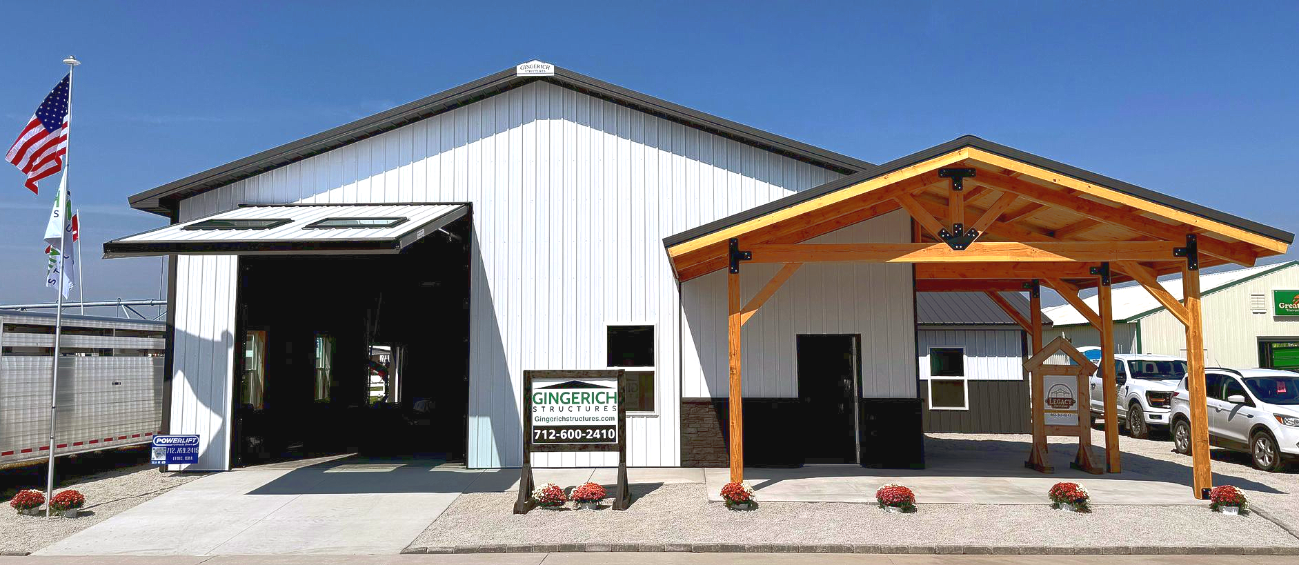 White metal building with open bay door, awning, and American flag.