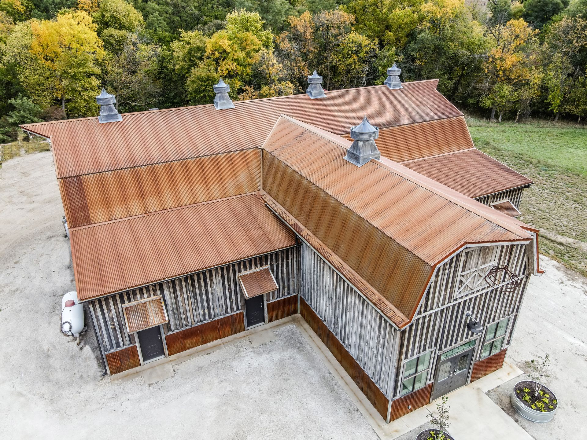 Rustic barn with weathered corrugated metal roof, gray and brown siding, and cupolas.