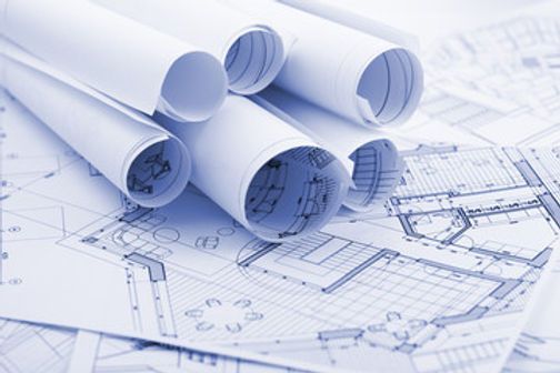 Blue architectural blueprints, rolled and stacked, with floor plan details visible.