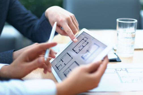 Two people reviewing floor plans on a tablet, pointing at the screen.