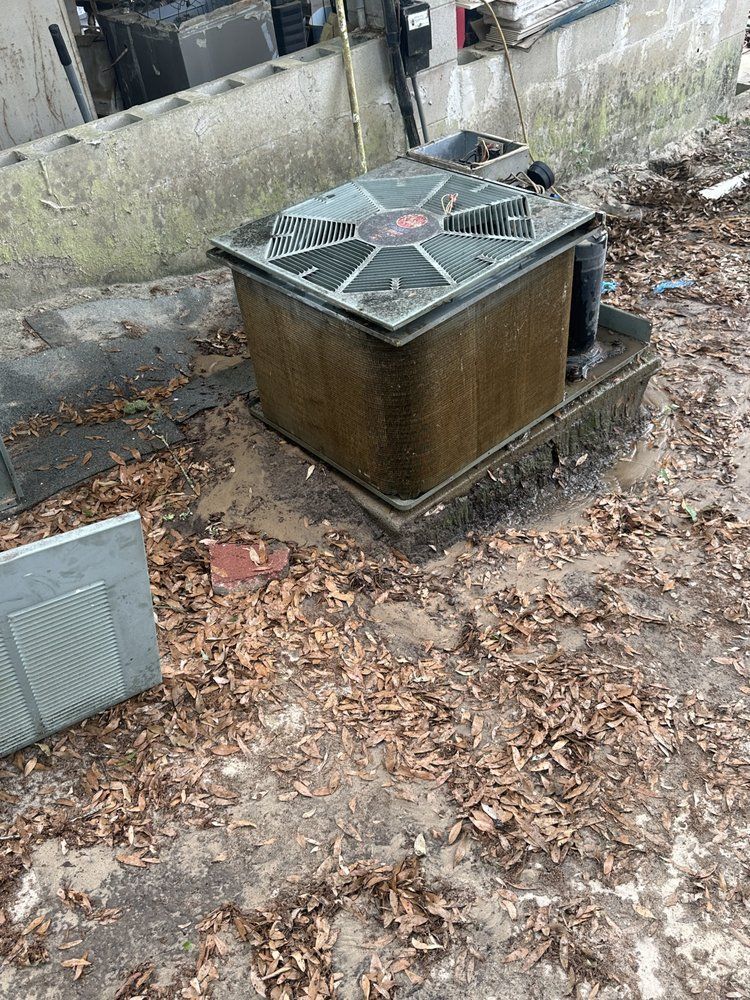 Electrical box with a green top and brown sides on a surface covered in leaves.