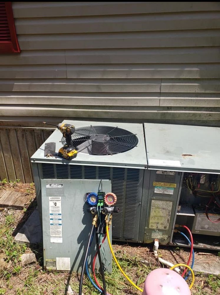 HVAC unit being serviced outdoors, with gauges attached. A drill rests on top.
