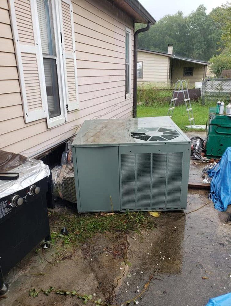 An air conditioning unit next to a house under an overcast sky.