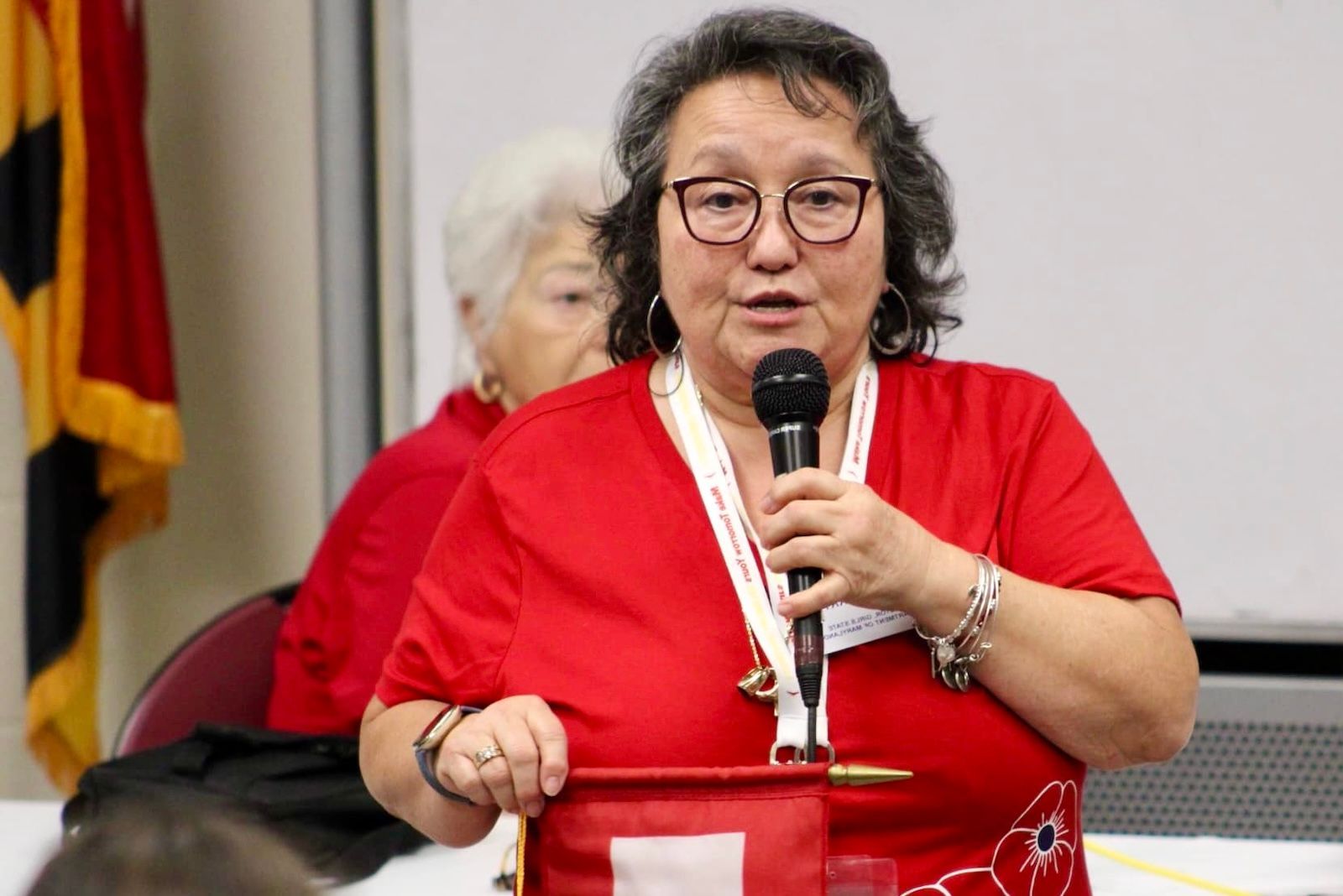 A woman in a red shirt is holding a microphone