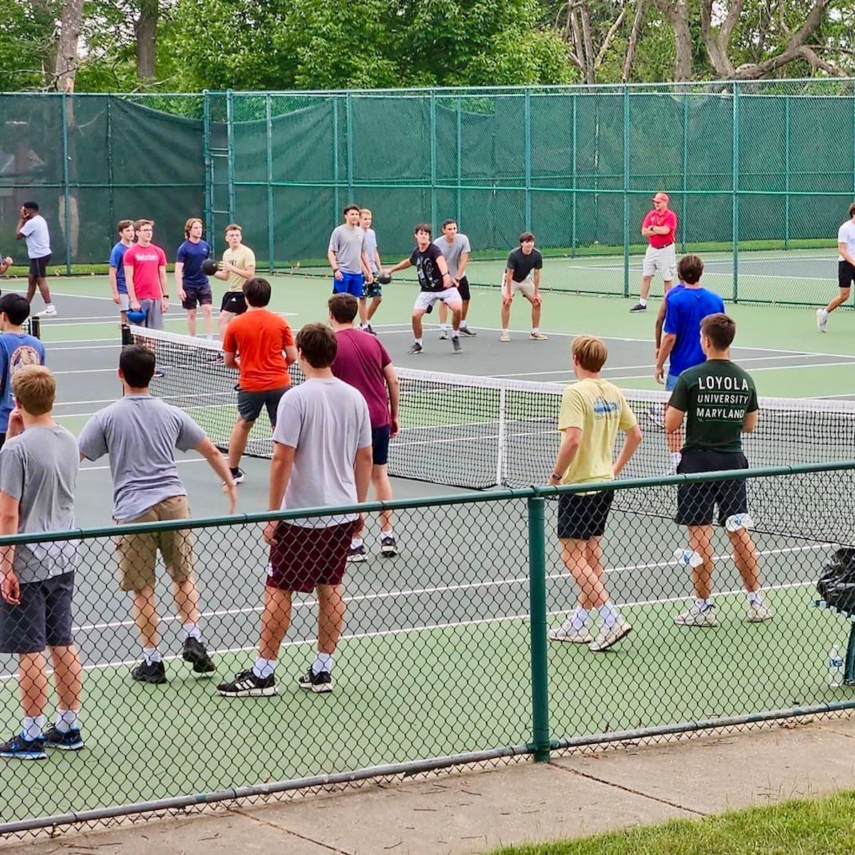 A group of young men are playing dodgeball on a tennis court