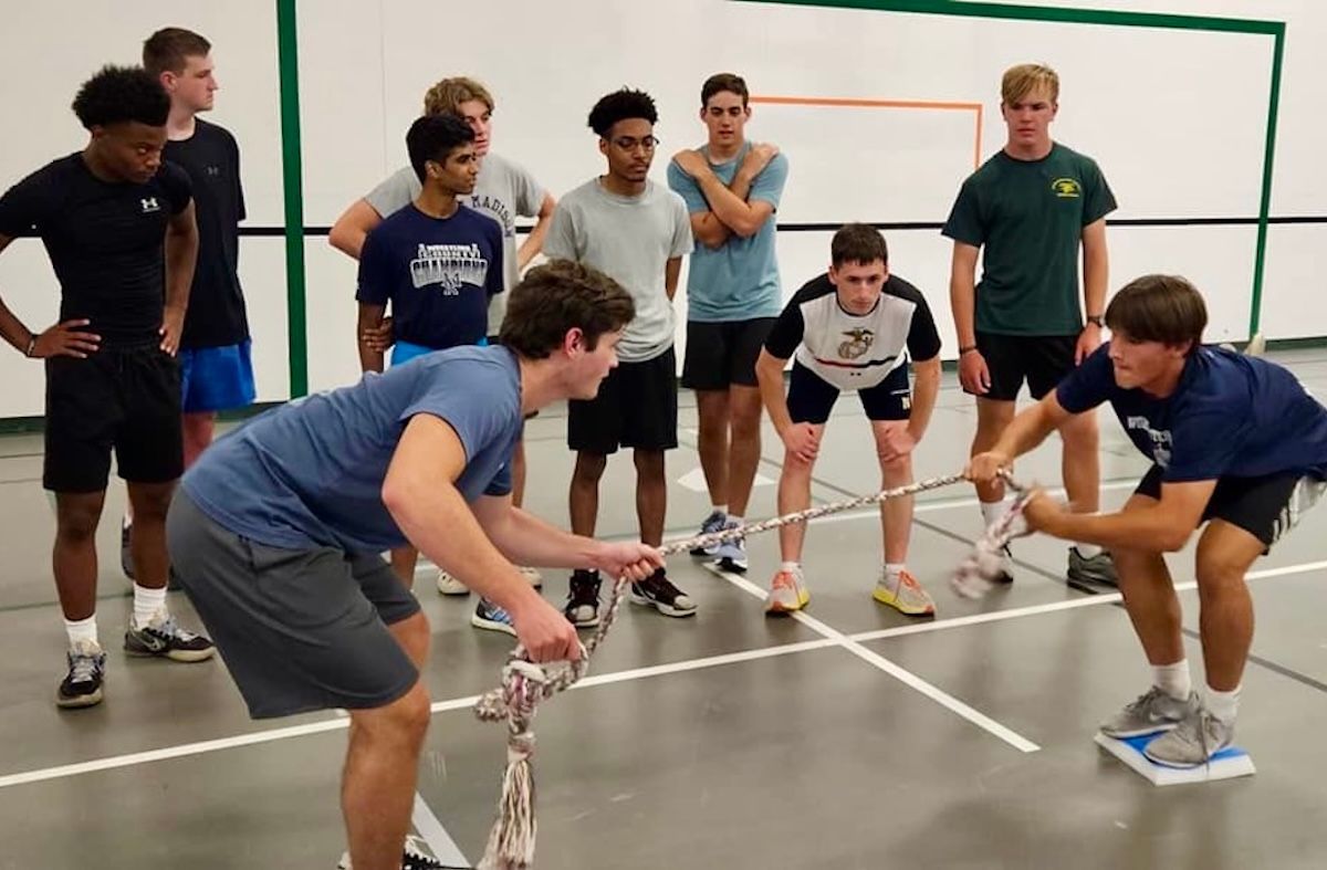 A group of young men playing tug of war in a gymnasium