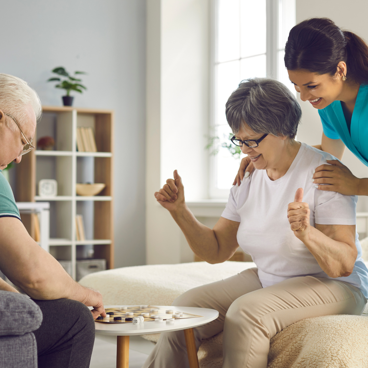 A woman is holding the hand of an elderly man while sitting in a chair.