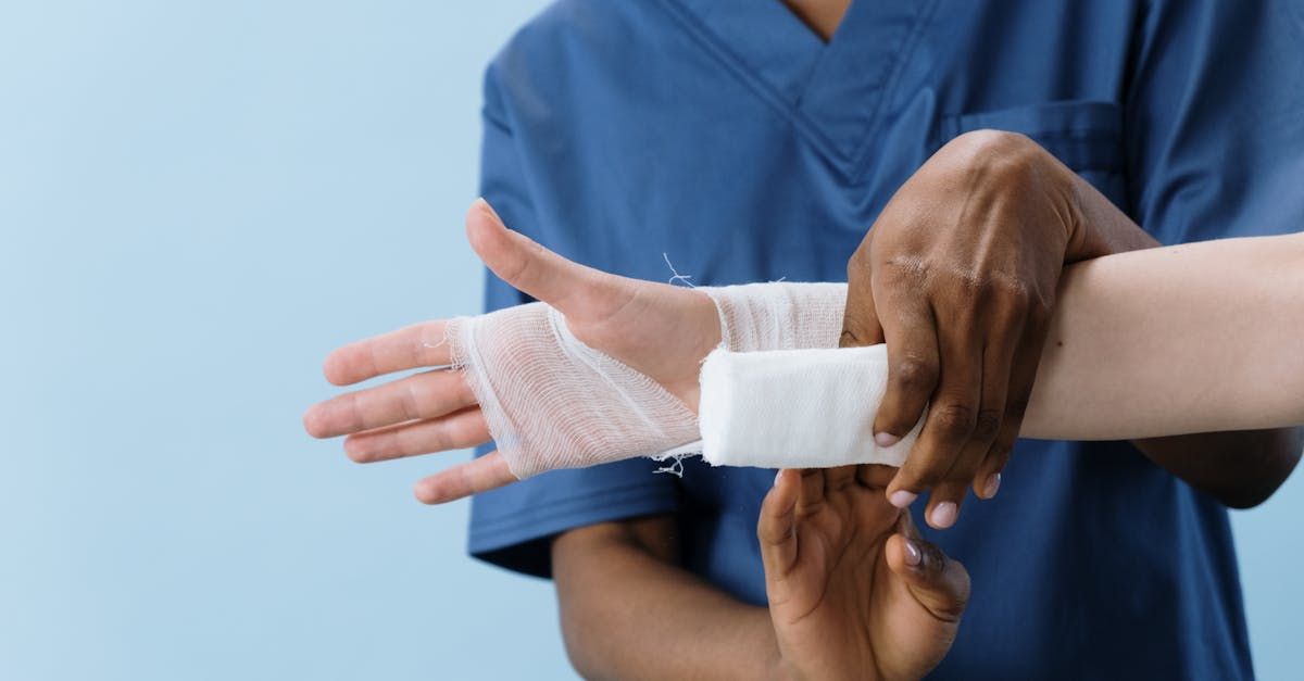 A nurse is wrapping a patient 's wrist with a bandage.