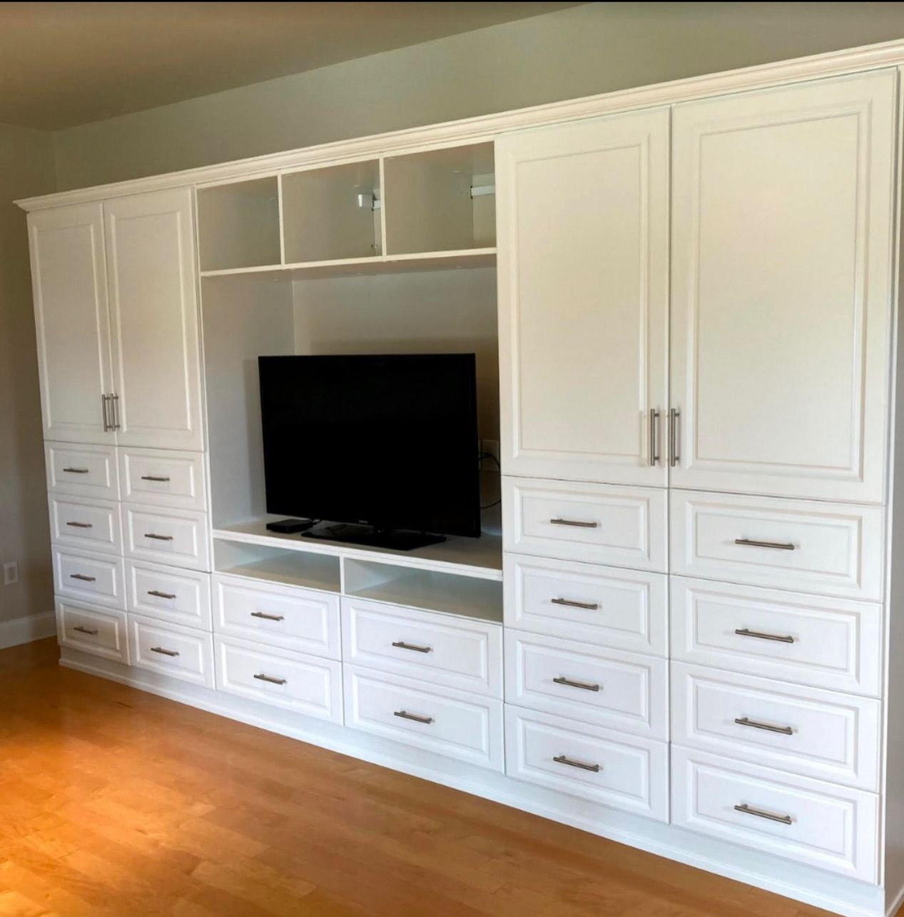 Built-in white media center with drawers, cabinets, and a television.
