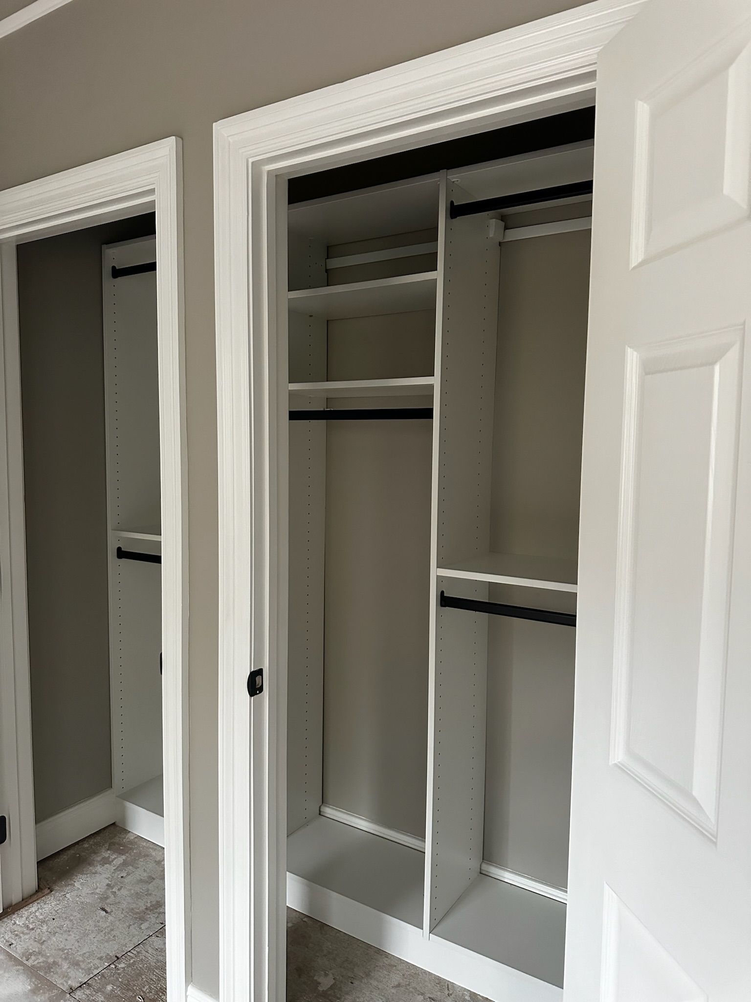 Open white closet with shelves and hanging rods. Gray walls, white trim and door.