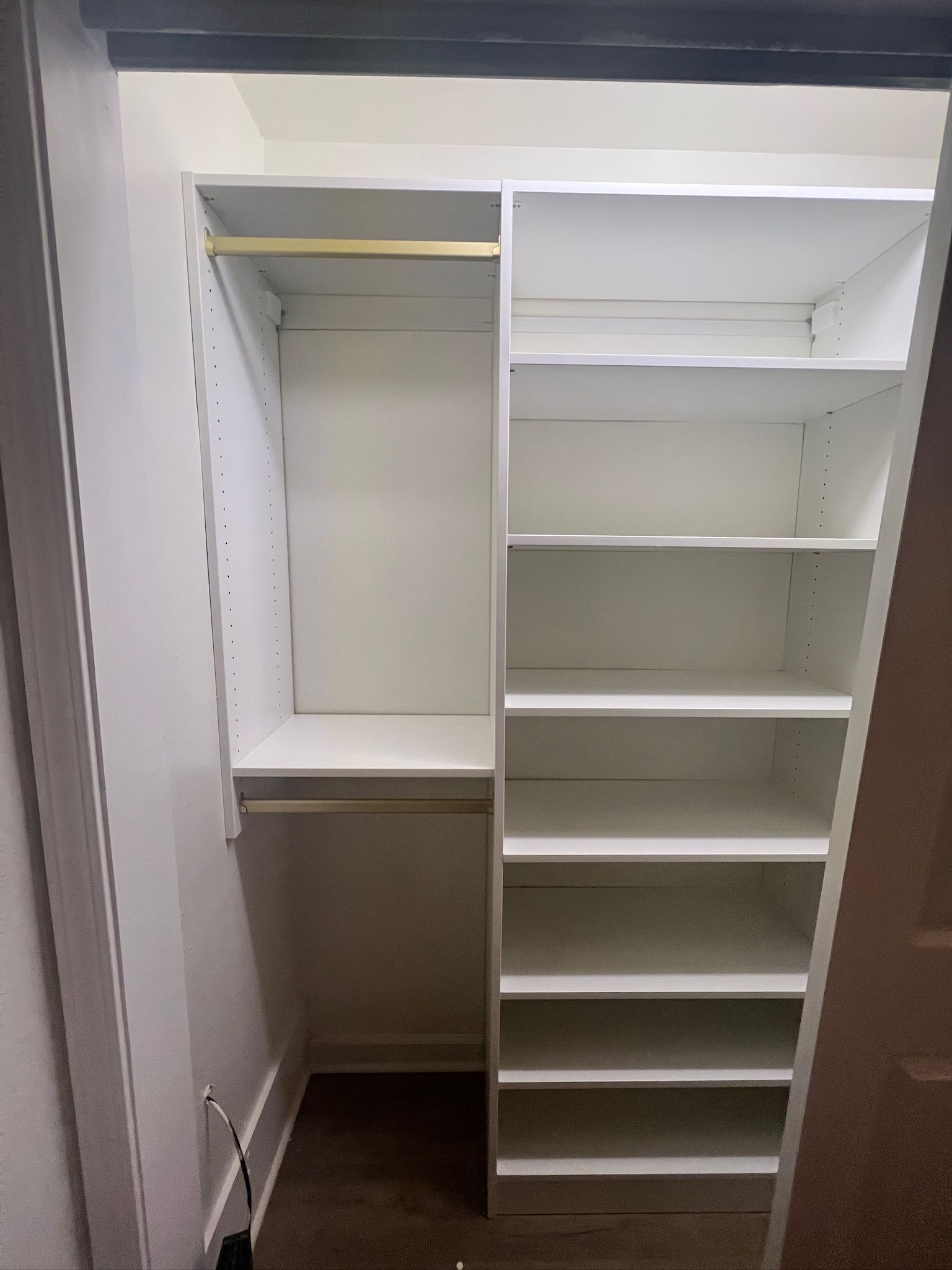 White closet with hanging rod, shelves, and a sloped side wall.