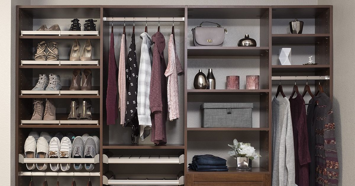 Wooden walk-in closet with shoes, clothes, and accessories in various shades of brown, pink, and gray.