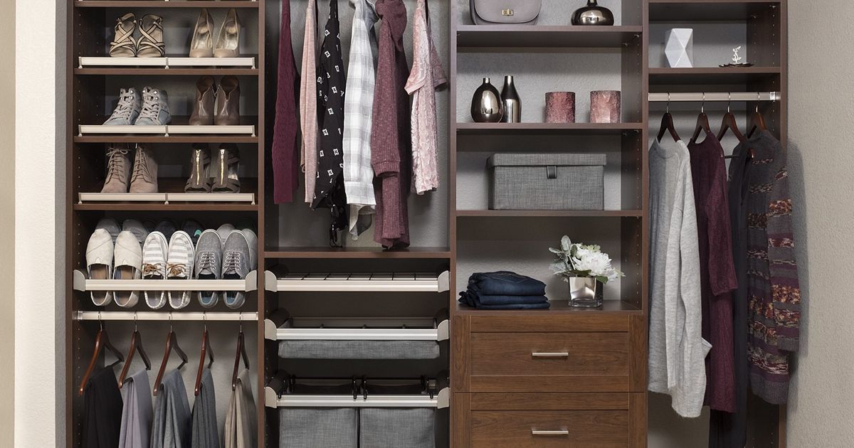 A walk-in closet with shoes, clothes, and accessories in a dark wood finish.