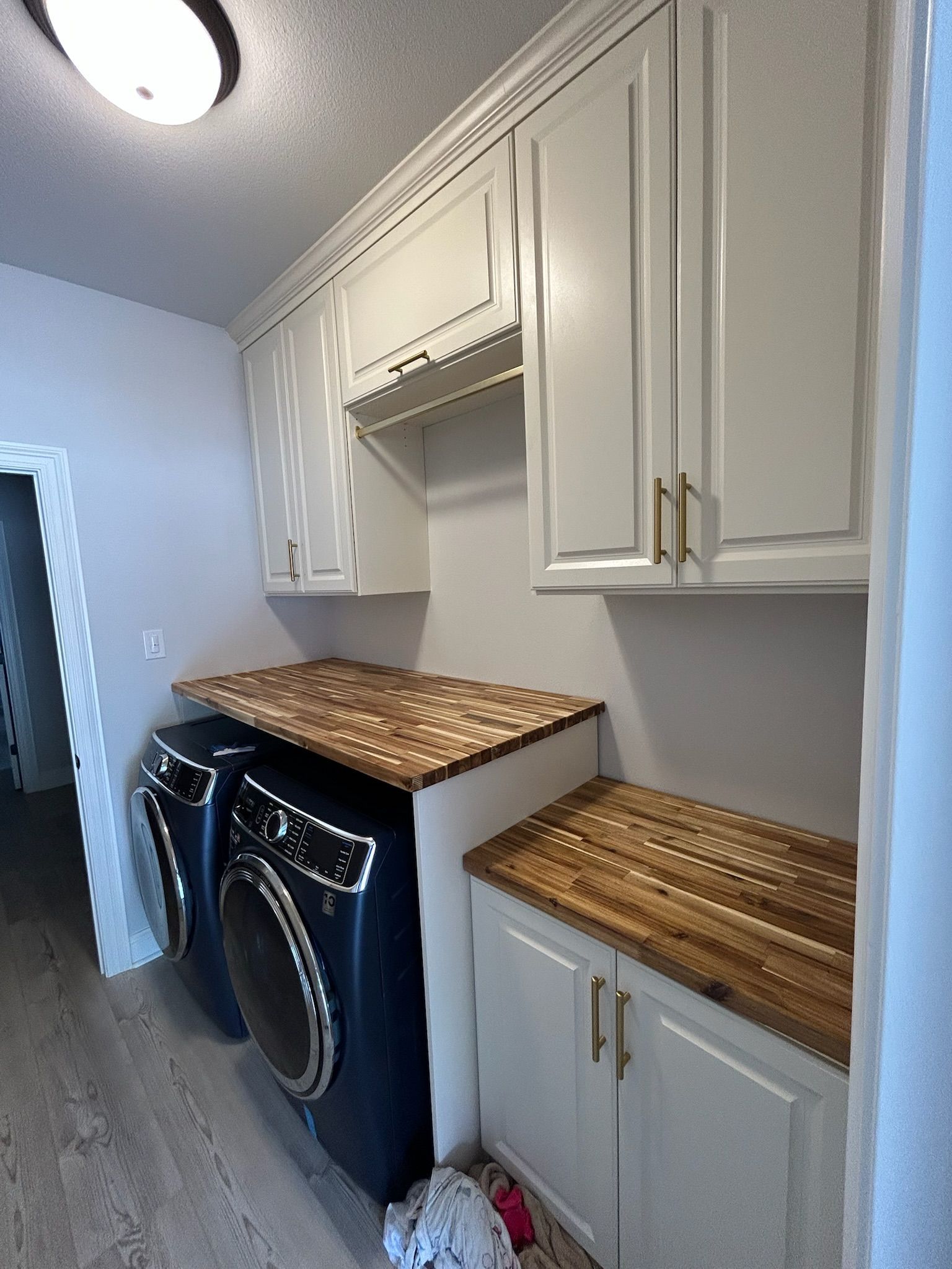 Laundry room with white cabinets, wood countertops, and blue washer/dryer.